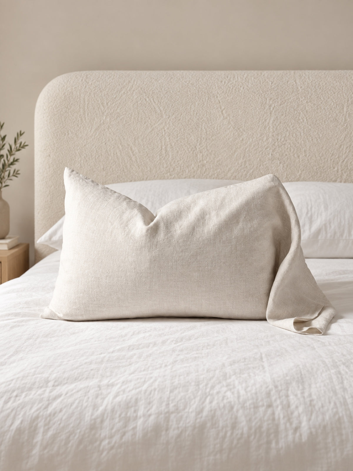 Funda de cojín de lino natural Modelo Light 50 x 70 cm, color Crudo, sobre cama con respaldo Elara